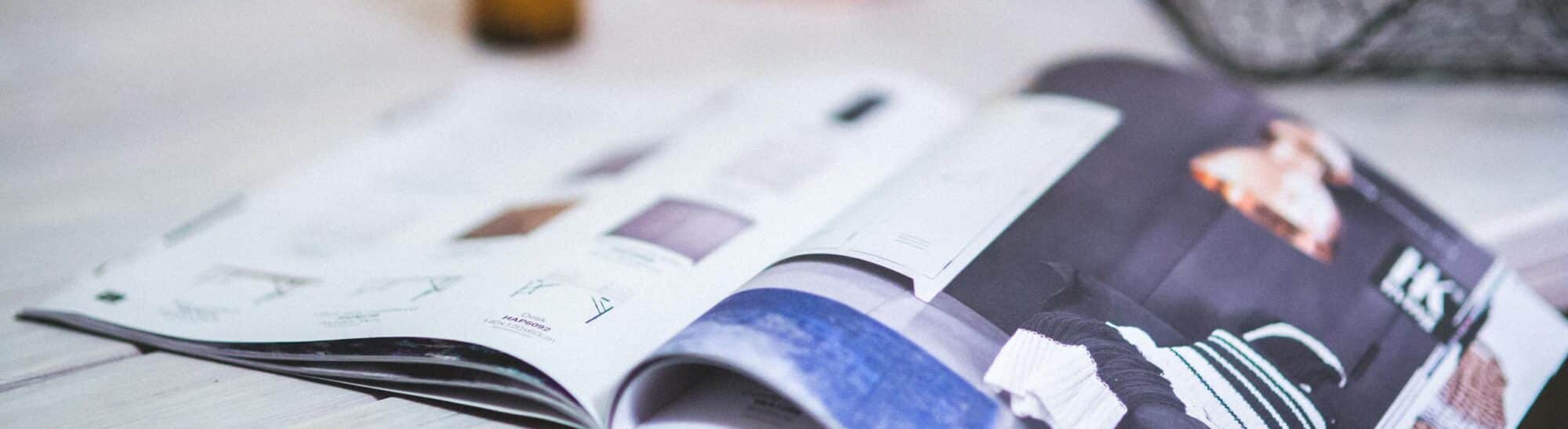 A stylish open magazine on a minimalistic desk with a blurred background.