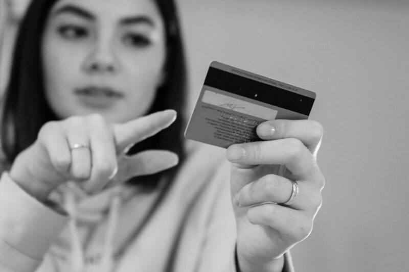 monochrome photo of woman pointing in a debit card